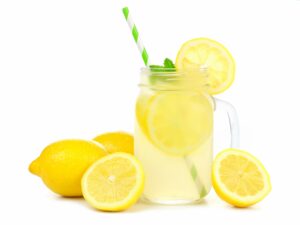 A glass of lemonade with lemons around it.