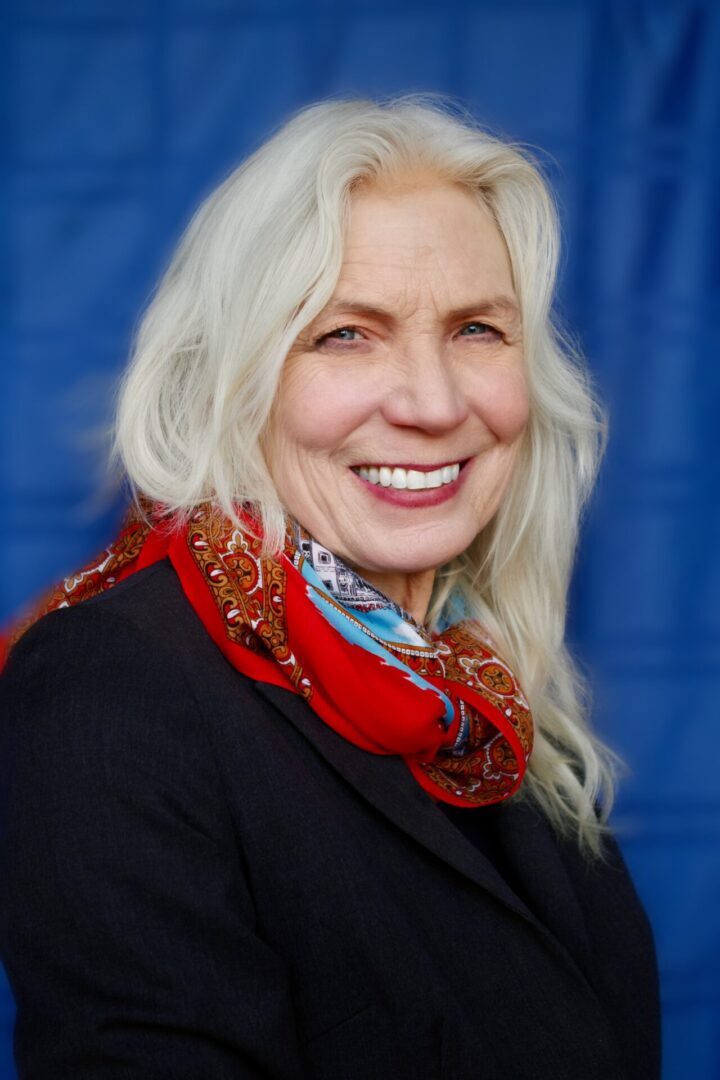 A woman with white hair wearing a red scarf.