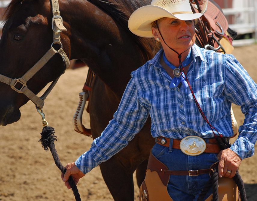 SALIDA, CO, USA - An older woman in traditional western wear and large belt bucket waits with her horse for the next event during a small Colorado rodeo. 2008